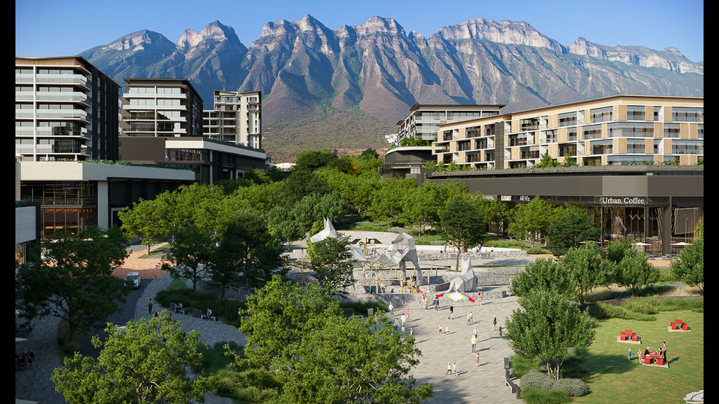 A park with buildings and trees with mountains in the background.